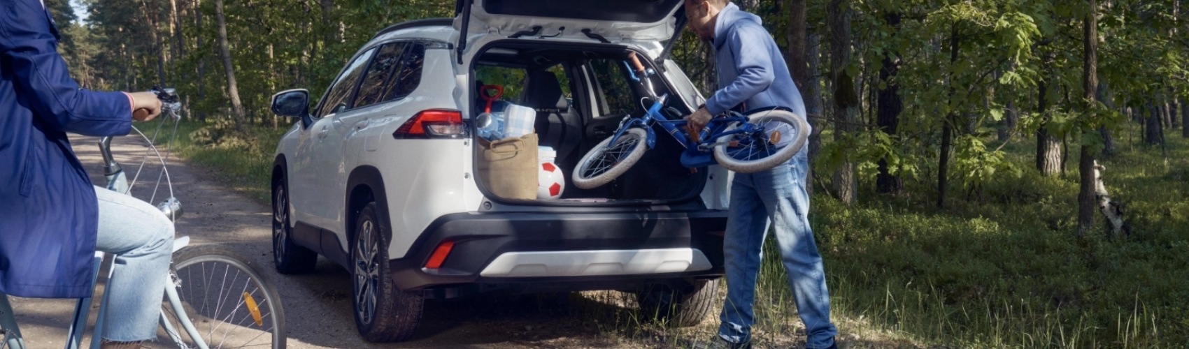 Rodina nakládá kola do auta v lese.