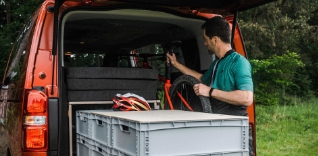 Muž nakládá kolo a vybavení do dodávky.