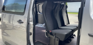 Vnitřek dodávky s třemi černými sedačkami.