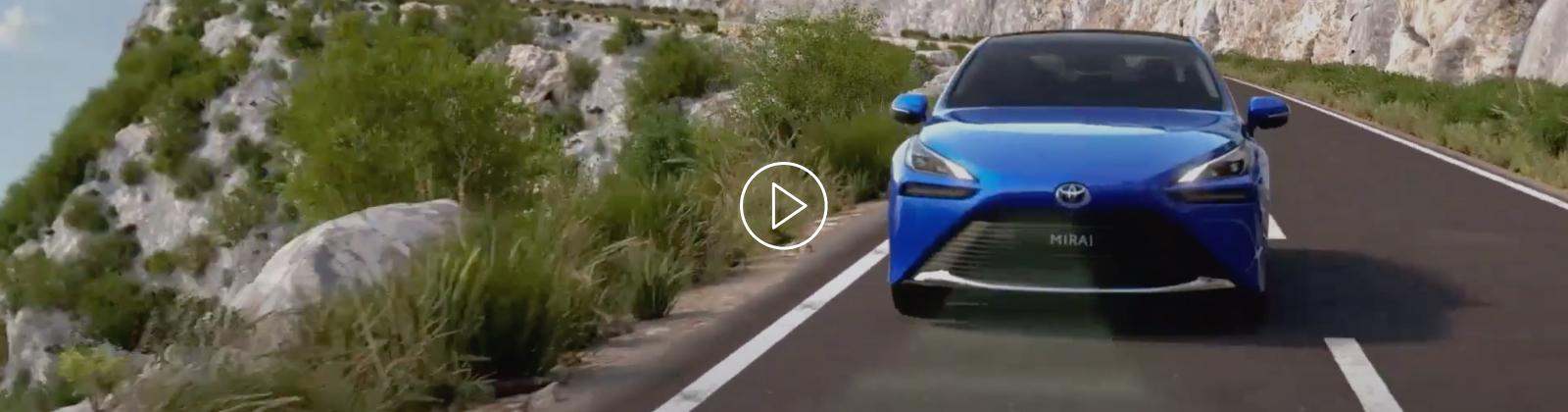 Modrý vůz Toyota Mirai jede po horské silnici.