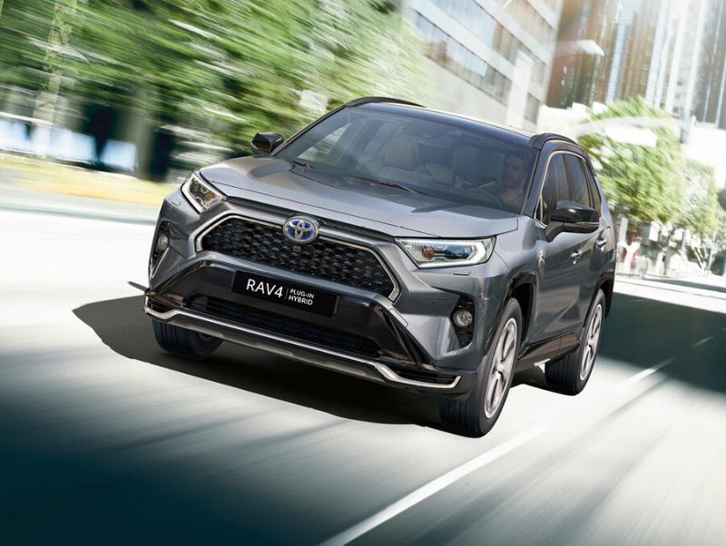 Šedé SUV Toyota RAV4 Plug-in Hybrid jede po městské ulici.