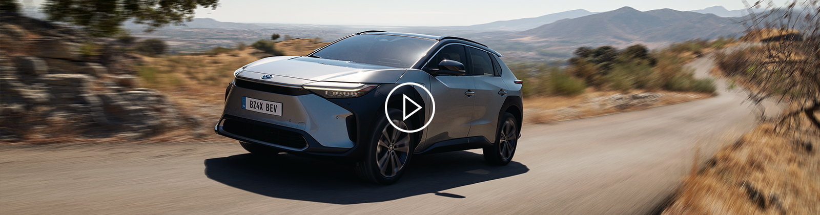 Stříbrné SUV Toyota BZ4X jede po venkovské silnici.