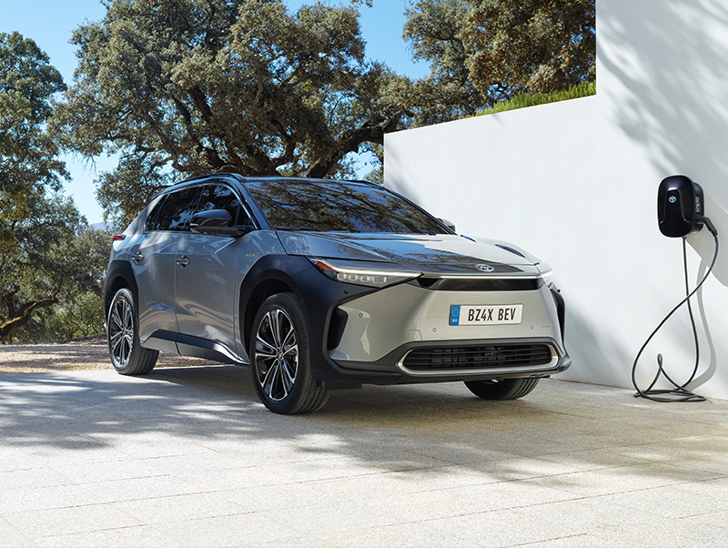 Stříbrné elektrické SUV Toyota bZ4X se nabíjí u zdi.