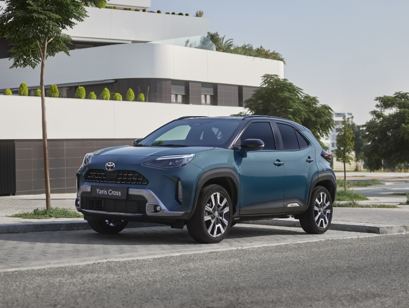 Zadní pohled na červený vůz Toyota Corolla Hybrid jedoucí po městské ulici.